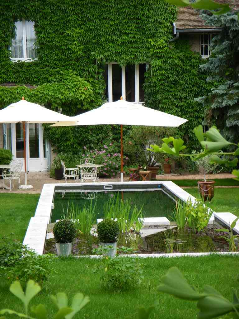 jardin moderne aménagement bassin d'eau déco florale plante parasol blanche table de jardin en métal