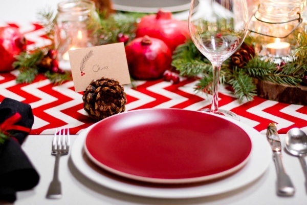 décoration-table-Noël-assiettes-rouges-branches-pin-pommes-pin-chemin-table-blanc-rouge décoration table de Noël