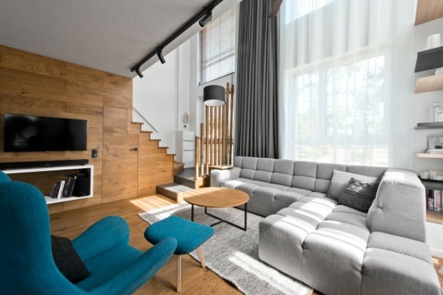 Aménagement salon loft moderne design idée canapé d'angle gris fauteuil bleu pouf table basse bois 