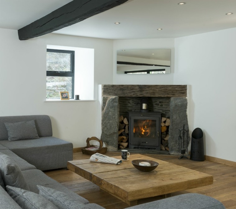 intérieur salon design table en bois basse canapé gris coussins cheminée habillage métal pierre bois idée