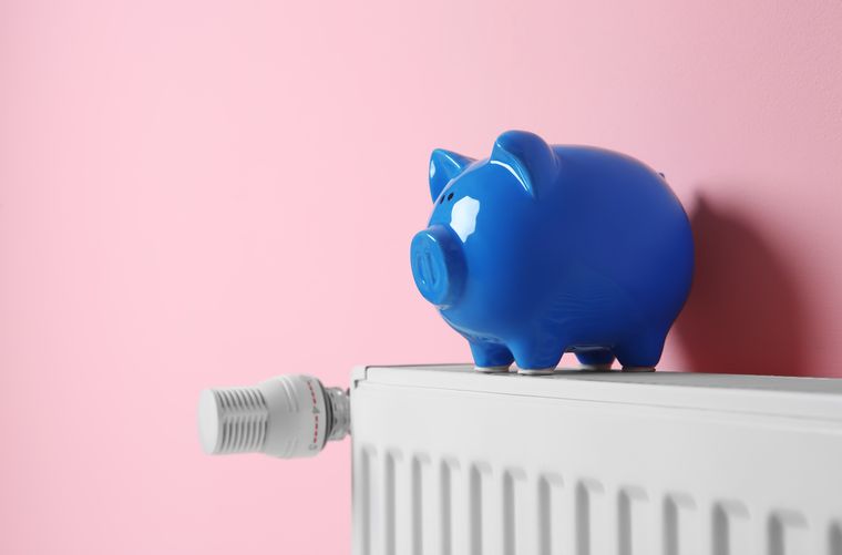 Heating radiator with piggy bank near color wall. Space for text