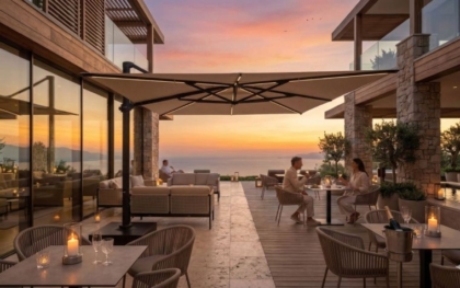 Grand parasol de terrasse haut de gamme sur une élégante terrasse avec vue sur la mer au coucher du soleil