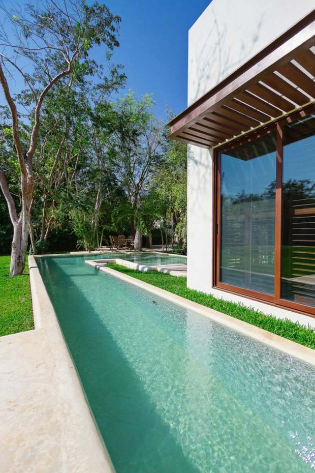 piscine eau turquoise disposée en coin autour maison